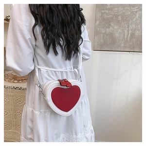 Detail of a chic heart-shaped leather crossbody bag worn by a model in a lifestyle setting