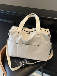 Large cream canvas travel duffel bag with front pockets and adjustable shoulder strap