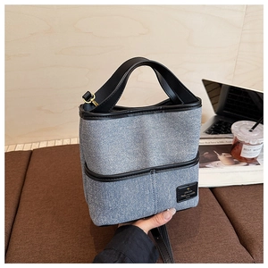 Détail du sac seau en denim bleu clair avec garnitures en cuir noir et bandoulière