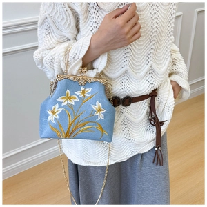 Detail of blue floral embroidery on a vintage style clasp bag with a gold chain strap