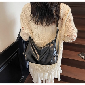 Detail of glossy black leather tote bag showing material texture and silver hardware