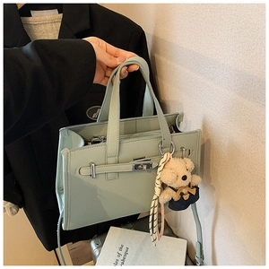 Detail of mint green lychee pattern leather handbag with belt buckle and bear charm