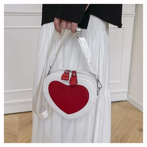 Detail of a heart-shaped crossbody bag featuring red and white color blocking