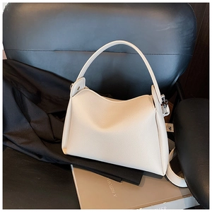 Detailed view of beige pebble grain leather texture and silver metal side buckles on handbag