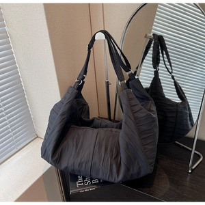 Detail view of black pleated nylon tote bag with silver metal rings and rich wrinkled texture