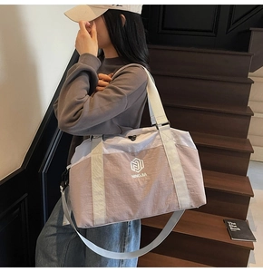 Detail of grey and pink large capacity travel bag with waterproof texture on wooden stairs