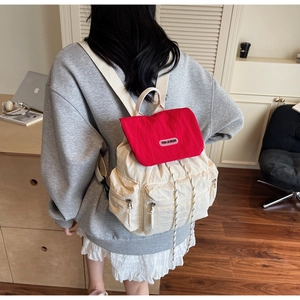 Detail of red and white contrast backpack with YOU JI BEAR logo and front zip pockets
