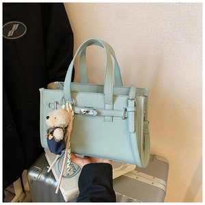 Detail of mint green lychee pattern handbag with bear charm and silk scarf decoration