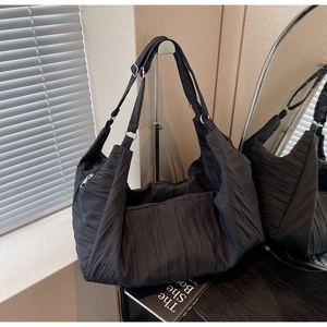Detail of black pleated tote bag showing the textured fabric and adjustable strap