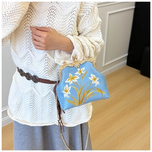 Detail of light blue embroidered canvas bag with gold chain and vintage pearl clasp