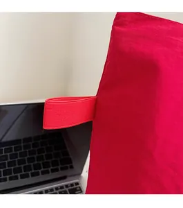 Detail of red nylon tote bag featuring durable webbing decoration and reinforced stitching