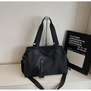 Detail of black nylon travel bag featuring reinforced handles and waterproof front pocket