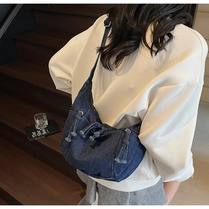 Detail of dark blue denim hobo bag with fringe tassels and adjustable shoulder strap