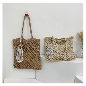 Detail of large woven beach bags in brown and beige with blue beaded tassels