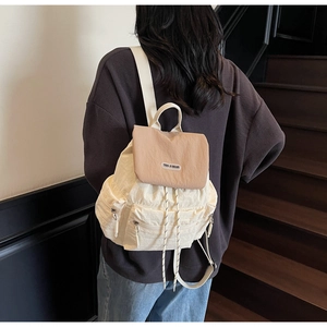 Detail of a beige and khaki nylon backpack with drawstring closure and magnetic flap
