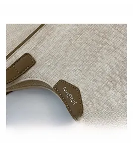Detailed close-up of beige canvas tote with brown leather trim and precision stitching