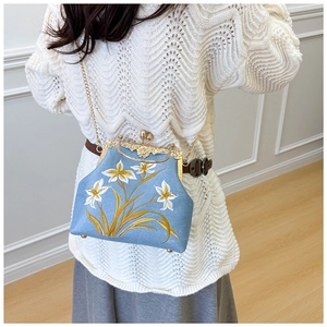 Detailed embroidery on blue fabric with vintage gold metal frame of the kiss-lock bag