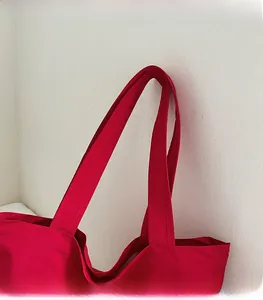 Detailed shot of the red tote bag showing reinforced stitching and comfortable shoulder strap