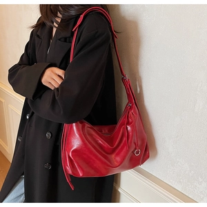 Detail of red glossy leather tote bag featuring a decorative long fringe and silver hardware
