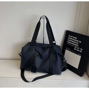 Detail of navy blue nylon travel bag with black handles and metal hardware