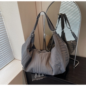Detailed view of the large pleated grey tote bag with adjustable shoulder strap on stand