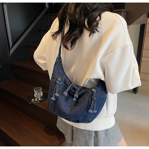 Detailed view of vintage denim hobo bag featuring multiple zippers and woven knot pullers