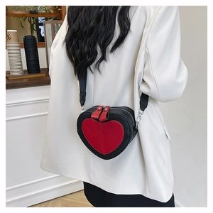 Detail of heart-shaped crossbody bag with red contrast insert on a white blazer