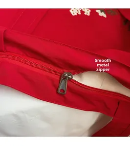 Detail of red embroidered tote bag featuring smooth metal zipper and floral patterns
