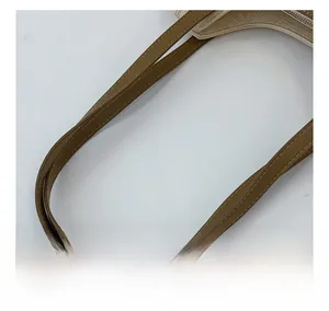 Detail of brown leather handles with white stitching on a beige canvas tote bag
