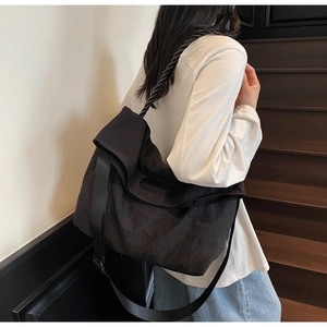 Detail view of black canvas crossbody bag with thick woven rope handle and wide strap