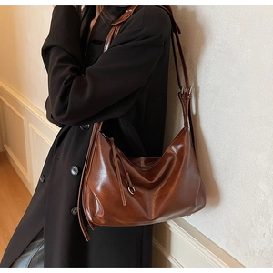 Brown soft leather tote bag on model showing large capacity and shiny finish