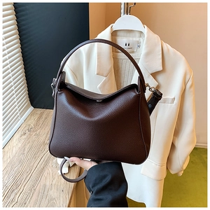 Macro detail of dark brown litchi grain leather handbag with fine stitching and hardware