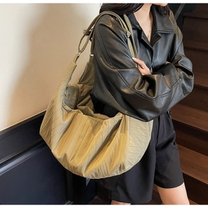 Detail of olive pleated nylon tote bag showing wrinkled texture and wide shoulder strap