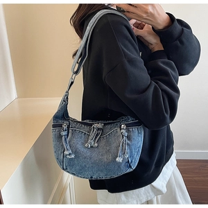 Detail of blue washed denim hobo bag with multiple zipper pockets and shoulder strap