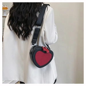 Crossbody view of a heart-shaped bag with red contrast on black PU leather and wide strap
