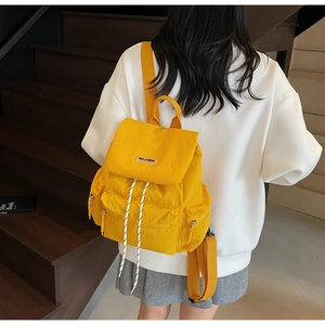 Detail of bright yellow nylon backpack featuring drawstring closure and side zipper pockets