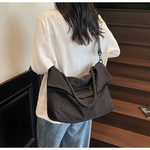 Detail of black nylon tote bag featuring thick braided handle and adjustable shoulder strap
