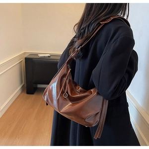 Detail of dark brown faux leather hobo bag with adjustable strap and metallic hardware