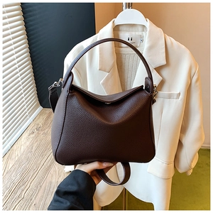 Detail of dark brown lychee leather handbag with fixed handle and metal side clips