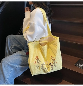 Detailed embroidery of colorful flowers on a vibrant yellow tote bag for women