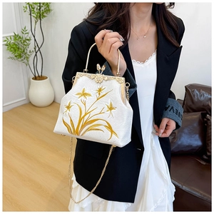 Detail of white vintage handbag with golden floral embroidery and metal frame closure