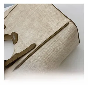 Close-up of the beige woven fabric texture and brown leather trim on the tote bag