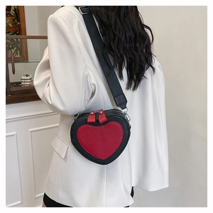 Rear view of model wearing a heart-shaped crossbody bag in black and red contrast leather