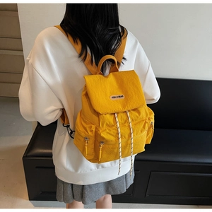 Rear view of a model wearing the large yellow nylon backpack with adjustable drawstrings