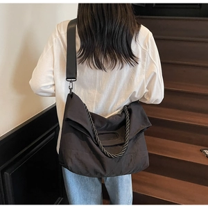 Rear view of a model wearing the large black crossbody tote bag with a unique rope handle