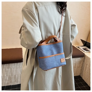 Sac seau en denim bleu avec garniture en cuir marron porté par un mannequin chic
