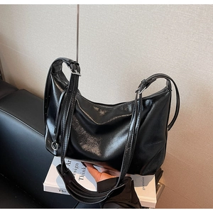Detailed shot of a black glossy leather hobo bag featuring silver adjustable hardware