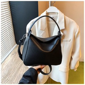 Detailed view of black lychee grain leather crossbody bag with silver hardware accents