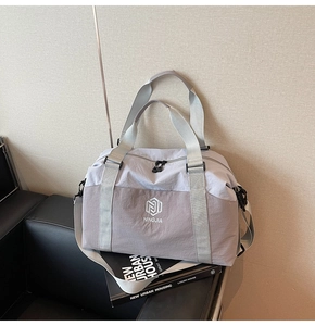 Detail of grey waterproof nylon travel bag with brand logo on a leather sofa