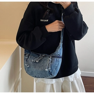 Detail of blue denim hobo bag with multiple zippers and wide strap in a mirror selfie